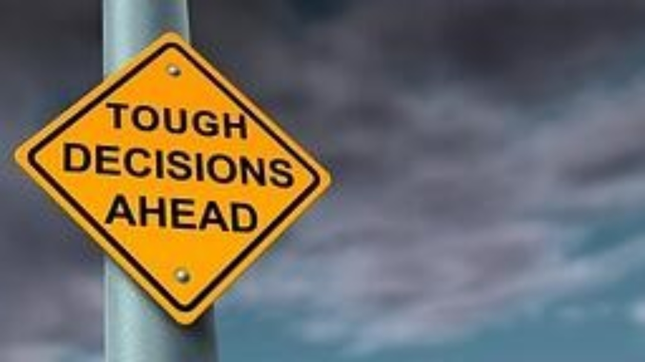 A road sign saying tough decisions ahead