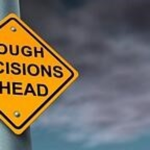 A road sign saying tough decisions ahead